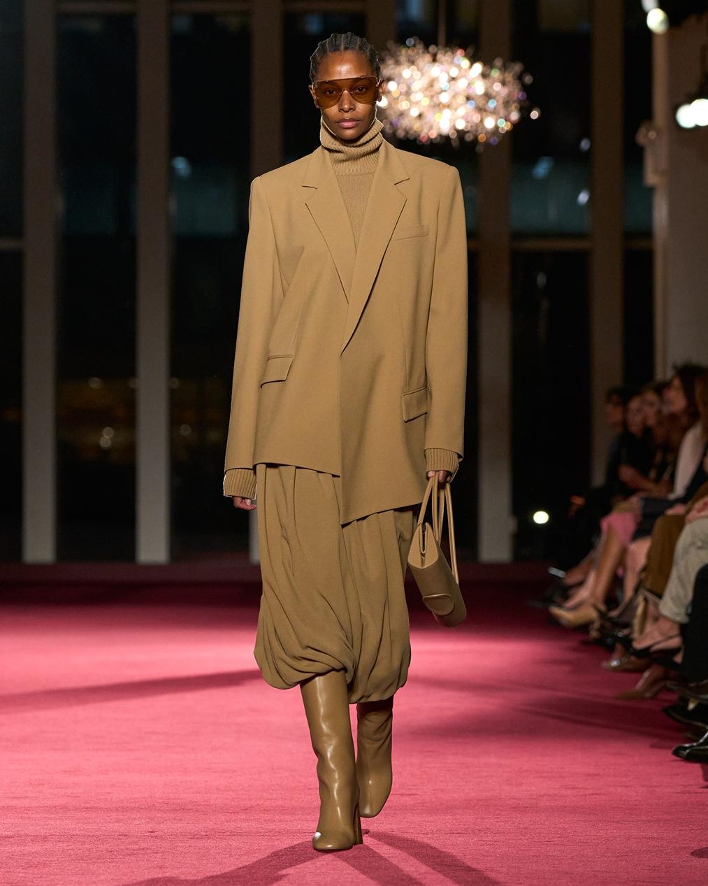 MICHAEL KORS以駝色寬版西裝外套搭配抓縐裙裝，彰顯都會女性剛柔並濟的柔韌印象。