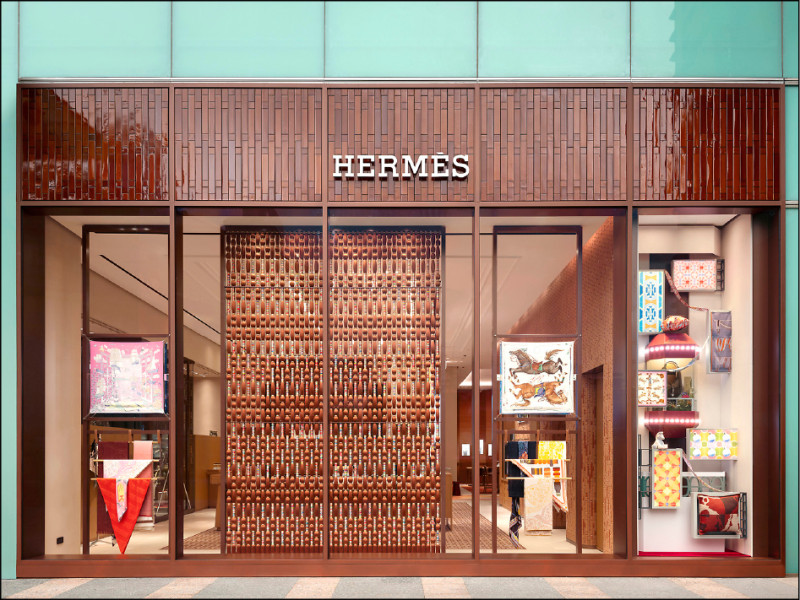 愛馬仕SOGO復興專門店外牆可見以絲巾打造如珠簾的裝置，右邊櫥窗中的紅色玻璃電梯，靈感則來自台北飯店的復古裝置。