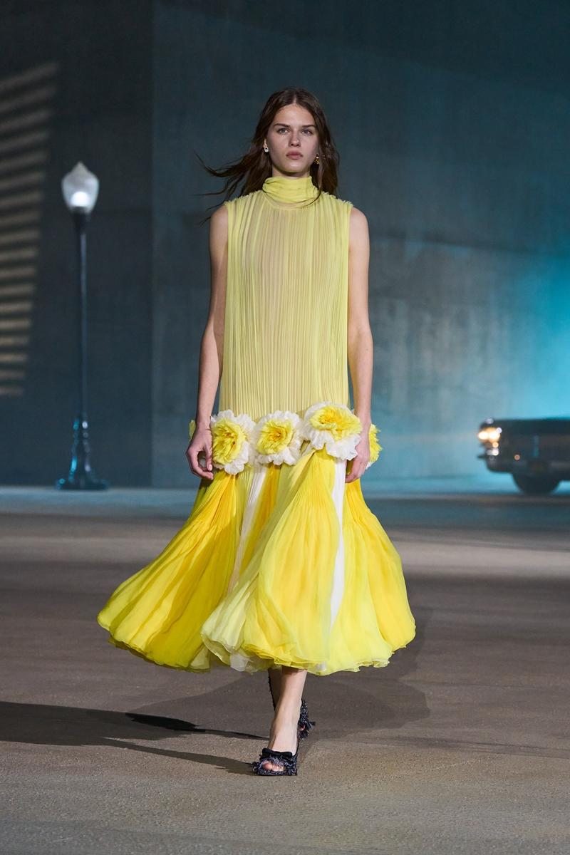 Dior2027早春度假系列以亮黃色薄紗洋裝揭開花卉主題，立體白黃花朵點綴腰際，讓輕盈裙襬在行進間帶出加州陽光般的鮮明存在感。（Dior提供）