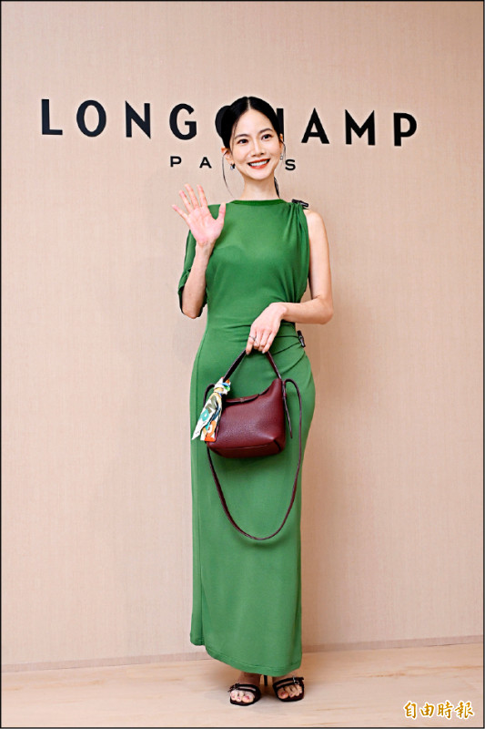 曾之喬演繹Longchamp 2026秋冬系列，她穿上抹茶色開衩連身裙（25,000元）搭配酒紅色高跟鞋（25,000元），手提Le Cadence水桶包（20,400元）勾勒優雅知性。（記者胡舜翔攝）