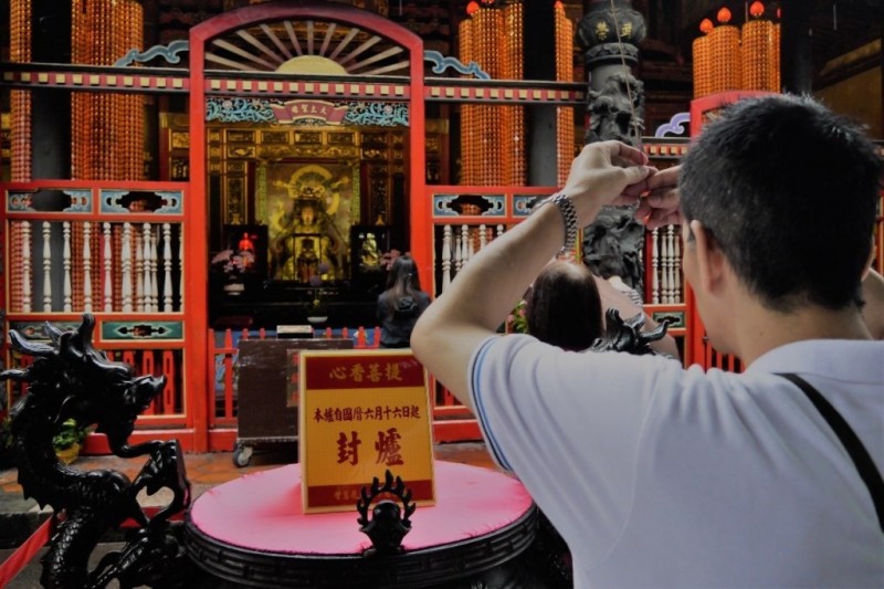 信眾在被封起的香爐前依舊高舉線香拜媽祖（林哲緯攝）