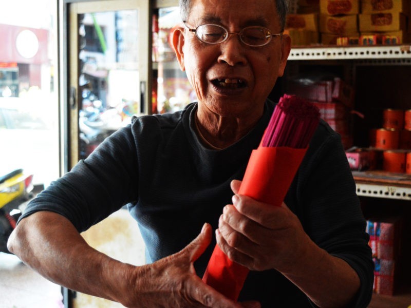 吳博男手上拿著剛包好的香，笑得開心，從16歲來吳萬春香鋪做工，已經快60年了。/圖片來源：顏麗家攝