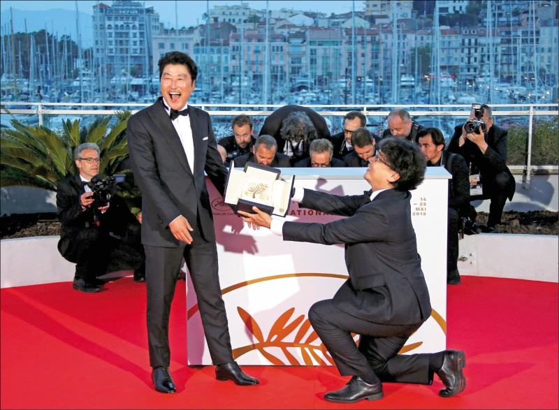 導演奉俊昊（右）以《寄生上流》獲得南韓首座金棕櫚獎，在坎城影展將獎項獻給男主角宋康昊。（路透）