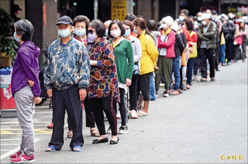 口罩實名新制兩週9片9日上路，台北一家健保藥局外購買口罩的民眾大排長龍。（記者簡榮豐攝）