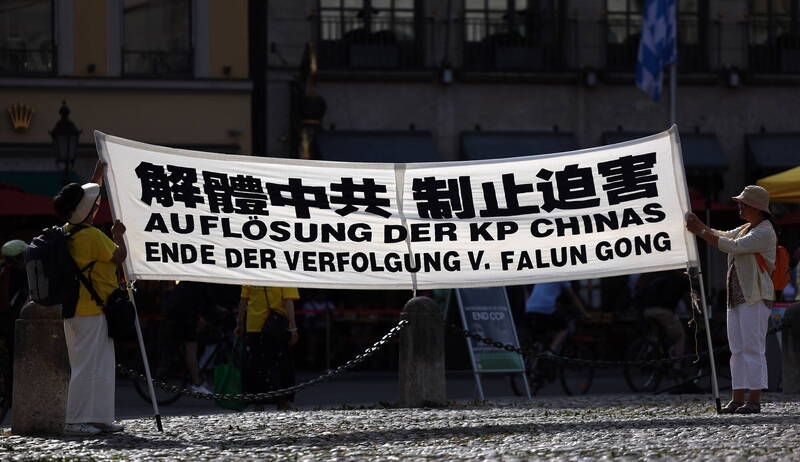圖為2023年，當時中國總理李強訪問德國期間，抗議者高舉抗議橫幅，上面寫著「解散中共，結束對法輪功的迫害」。（歐新社）