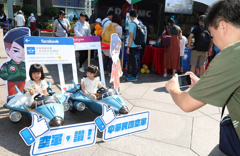 國防部31日下午在台北101水舞廣場舉辦「能戰嘉年華」活動，適逢週末假期，許多民眾帶著家中小朋友到場共襄盛舉，有家長為孩子與現場展示的小飛機合影留念。（中央社）