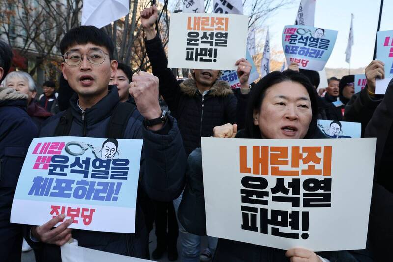 韓國首爾國民議會外舉行示威活動，抗議者舉著標語牌，呼籲逮捕並罷免韓國總統尹錫悅。（歐新社）