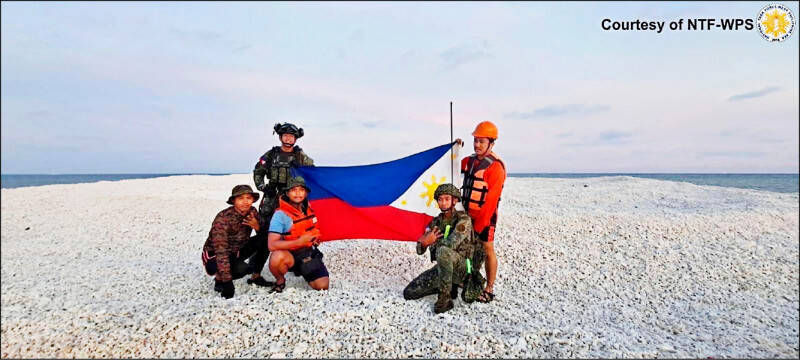中菲在南沙群島鐵線礁上演「插旗競賽」，雙方派人展示國旗，互控對方侵犯主權。圖為菲方人員登上鐵線礁，展示菲國國旗。（法新社檔案照）