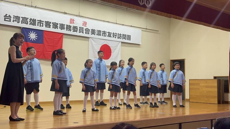 台日友好。高市客家兒童到日本岐阜縣美濃市役所交流演唱，會場懸掛台日國旗，顯示兩國堅定友誼。（圖由客委會提供）