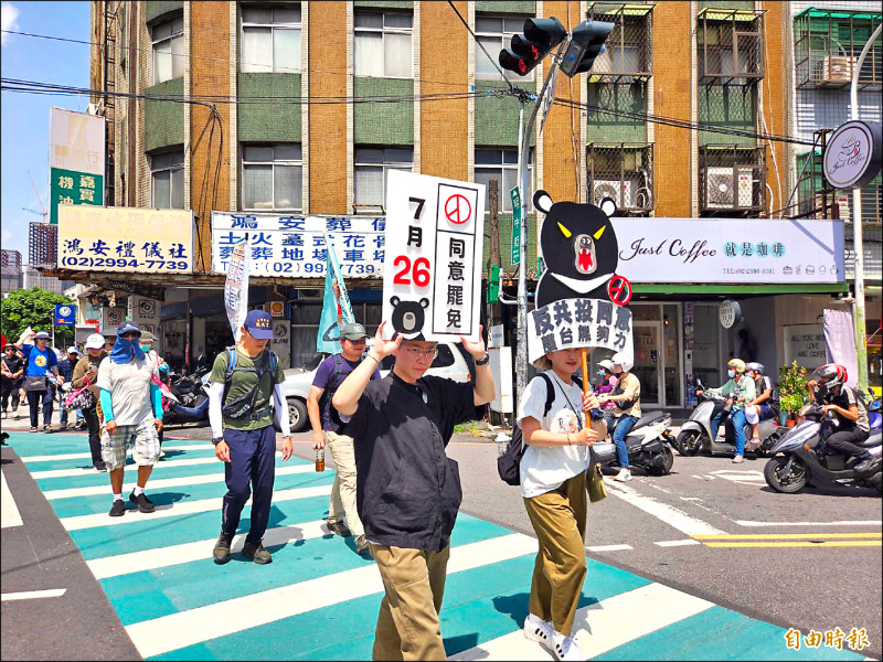 參與「護國大遶境」徒步護台灣行動的人員高舉標語，呼籲民眾投下同意罷免票。（記者賴筱桐攝）