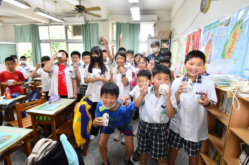 學童喝牛奶面對鏡頭比「耶」高興的心情全寫在臉上。（資料照）