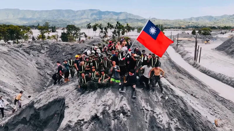 鏟子超人和國軍弟兄們登上淤泥堆成的土丘揮舞國旗，象徵台灣人將在2025年開始推進「光復」花蓮。（張世賢提供）