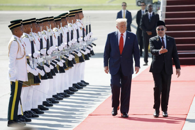 美國總統川普（左）26日飛抵馬來西亞吉隆坡，展開亞洲行首站訪問，由馬來西亞首相安華（右）親自迎接並陪同檢閱儀隊。（彭博檔案照）