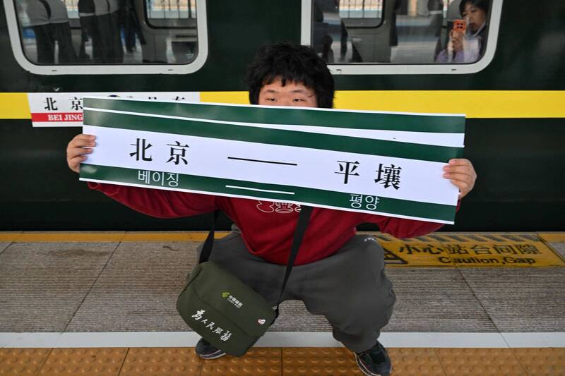 停駛6年的北京—平壤跨國客運列車復駛，背後的核心目標，卻是將金正恩牢牢綁在北京的影響範圍之內。圖為旅客手持「北京-平壤」橫幅，站在開往平壤的K27次列車前。（法新社檔案照）