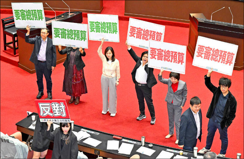 今年度中央政府總預算案，從去年八月底函送立法院審議以來，持續在程序委員會遭到在野黨杯葛，遲遲未能交付委員會審查。圖為民進黨立委高舉標語，抗議藍、白立委阻擋總預算案。（資料照）