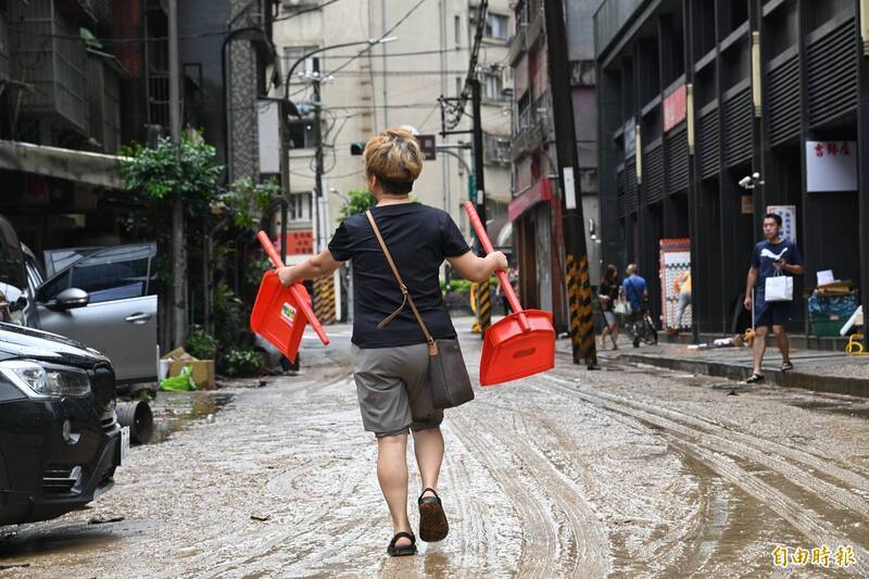 北市內湖25日降下豪雨，圖為內湖路三段一帶淹水，水退後都是泥濘，受災民眾打掃善後。（資料照）